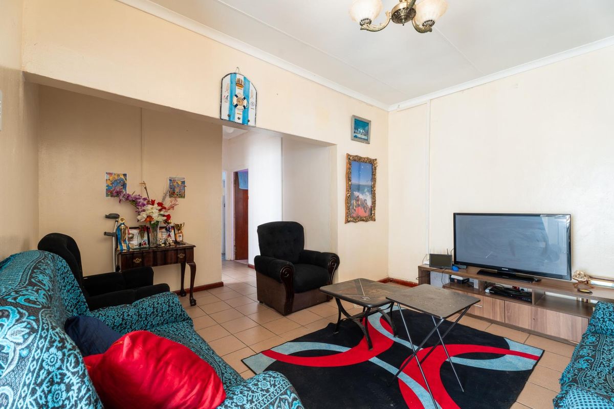 A living room featuring tiled flooring and an open archway leading to a hallway, with neutral wall tones and standard ceiling finishes.
