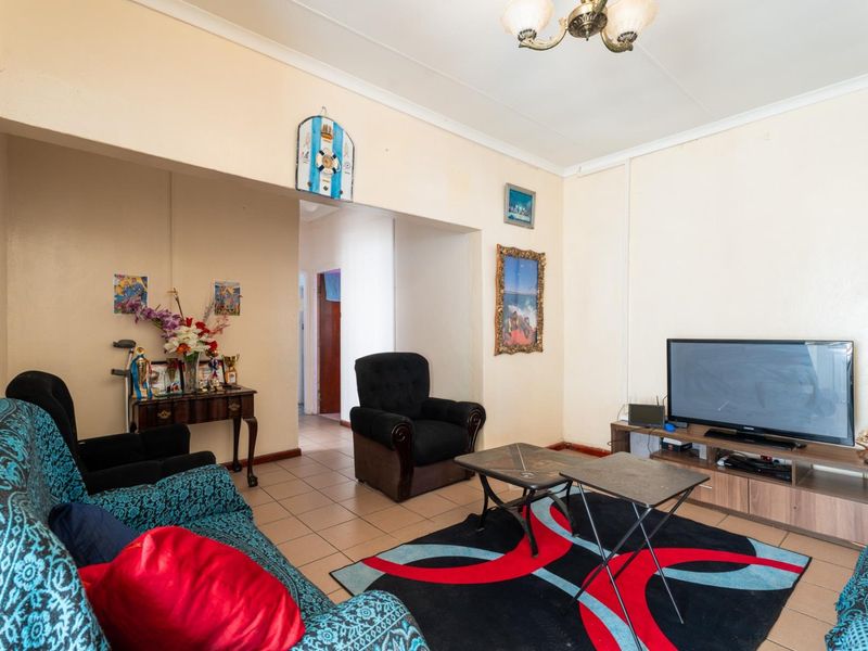 A living room featuring tiled flooring and an open archway leading to a hallway, with neutral wall tones and standard ceiling finishes.