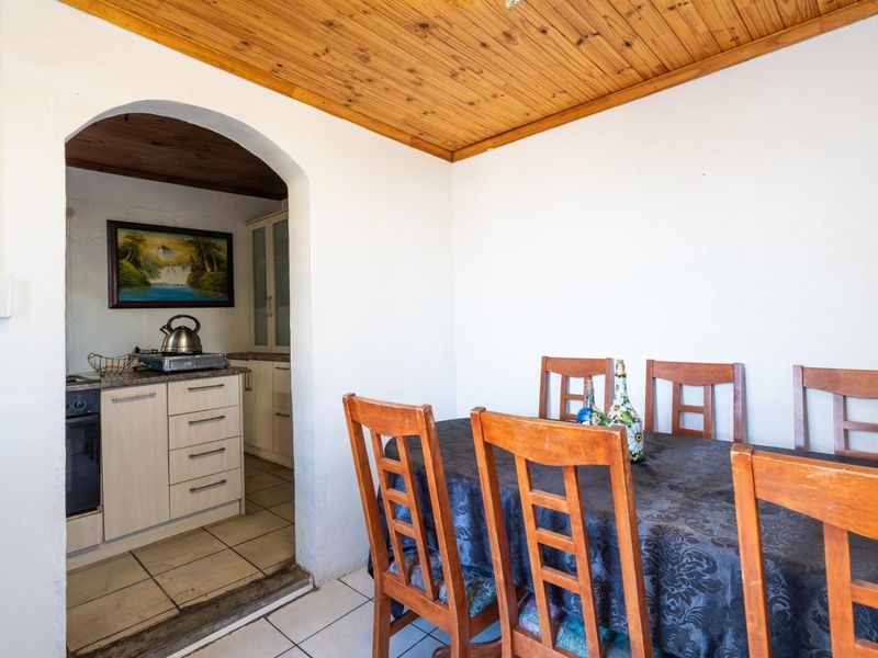 Open plan dining area featuring a timber ceiling and tiled flooring, with an arched transition into a functional kitchen space.