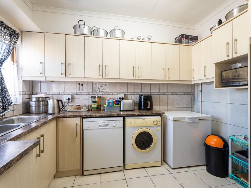 Functional kitchen featuring laminate cabinetry, tiled backsplash, and dedicated space for laundry appliances and a chest freezer.