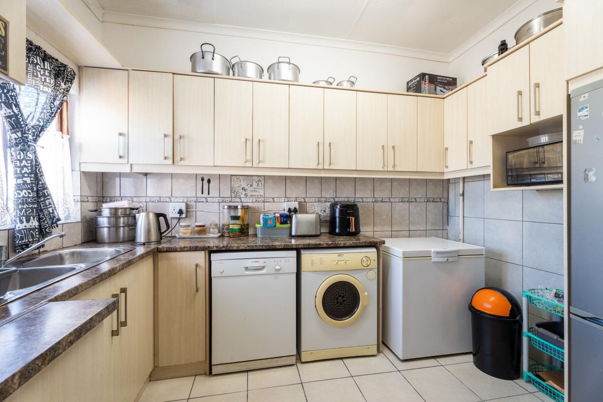 Functional kitchen featuring laminate cabinetry, tiled backsplash, and dedicated space for laundry appliances and a chest freezer.