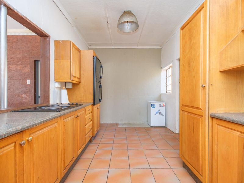 A dated kitchen featuring wooden cabinetry, built-in oven, gas hob, and tiled flooring, offering significant potential for a modern renovation.