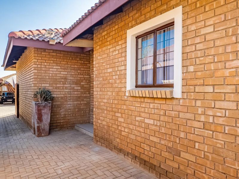 A view of the townhouse exterior featuring a face brick facade, tiled roof, and paved driveway area.