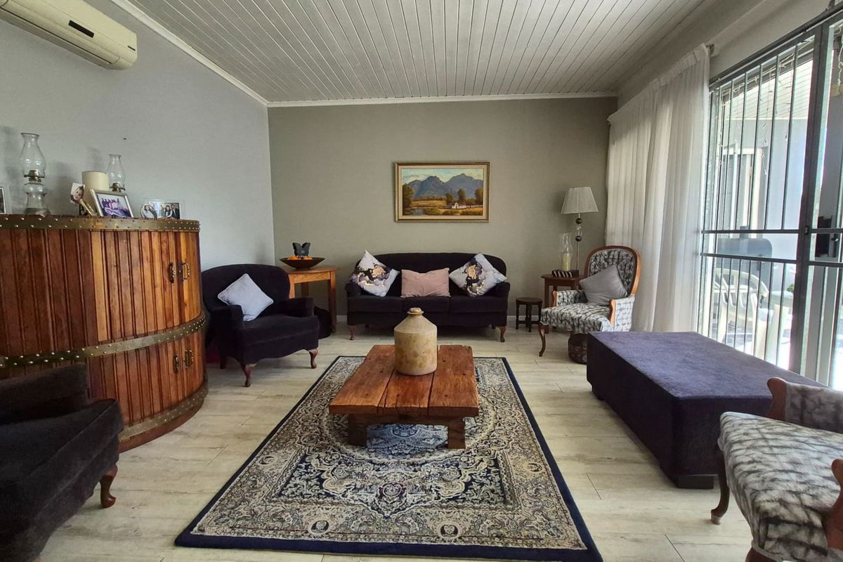 A comfortable living room featuring timber-look tile flooring, a tongue and groove timber ceiling, and a split-system air conditioner with access to the patio.