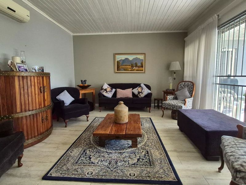A comfortable living room featuring timber-look tile flooring, a tongue and groove timber ceiling, and a split-system air conditioner with access to the patio.