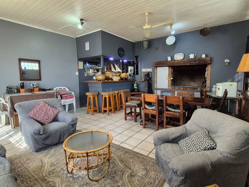 Open-plan living area featuring a built-in bar, a traditional brick fireplace, tiled flooring, and a timber ceiling.