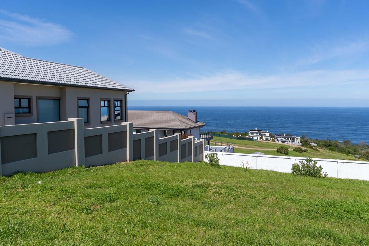 A scenic view of the ocean from a vacant residential plot, featuring well-maintained boundary walls and neighboring coastal properties.