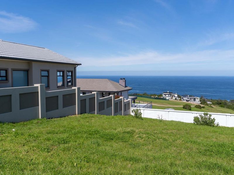 A scenic view of the ocean from a vacant residential plot, featuring well-maintained boundary walls and neighboring coastal properties.