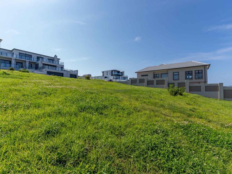 A view of a vacant residential plot featuring a gentle slope and surrounding established residential properties.