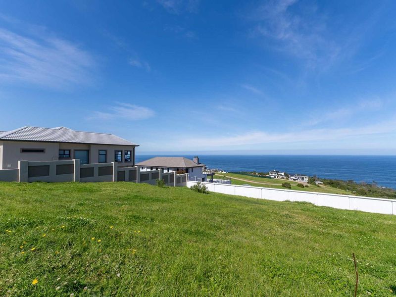 A scenic view of the coastal landscape and ocean from the vacant residential land, featuring established boundary walls and neighboring properties.
