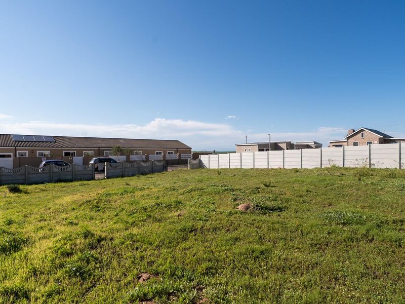 A vacant residential plot featuring established grass cover and enclosed by precast concrete boundary walls in a developed neighborhood.