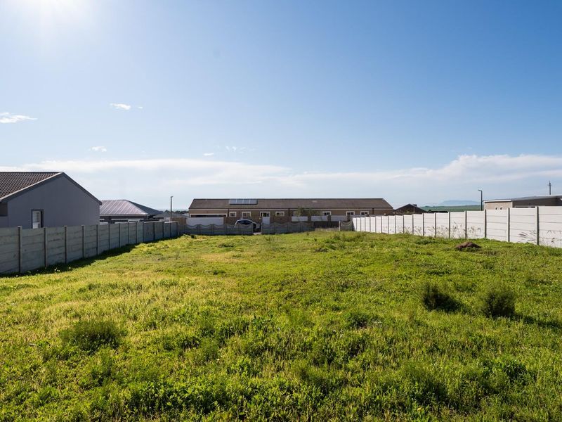 A vacant residential plot featuring a level grassed area enclosed by precast concrete boundary walls, offering a blank canvas for future development.
