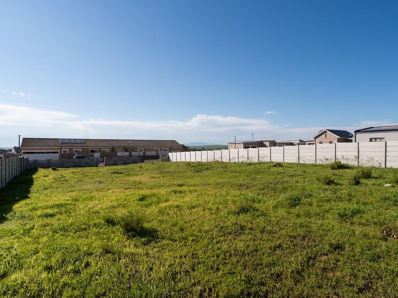 A vacant residential plot of land enclosed by precast concrete boundary walls, offering a clear space ready for development.