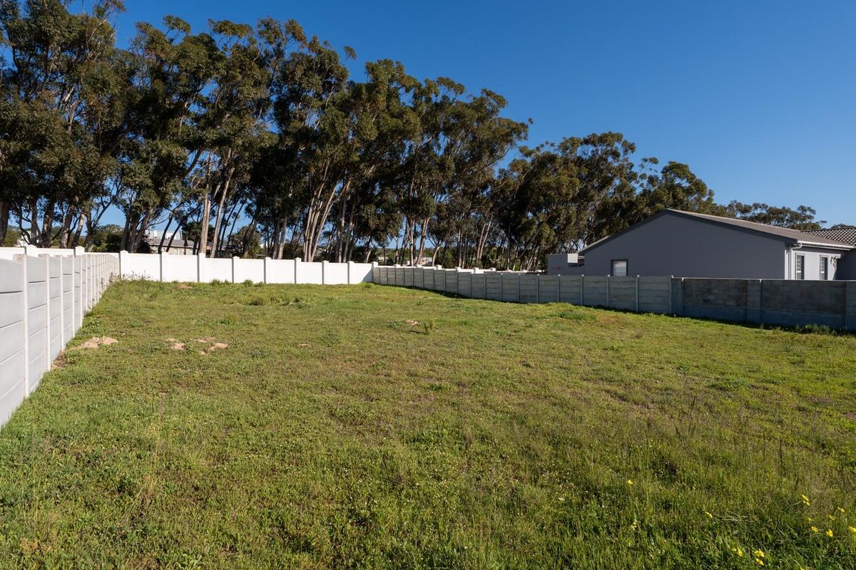 A vacant residential plot featuring a grass lawn and secure precast concrete boundary walls, ready for development.