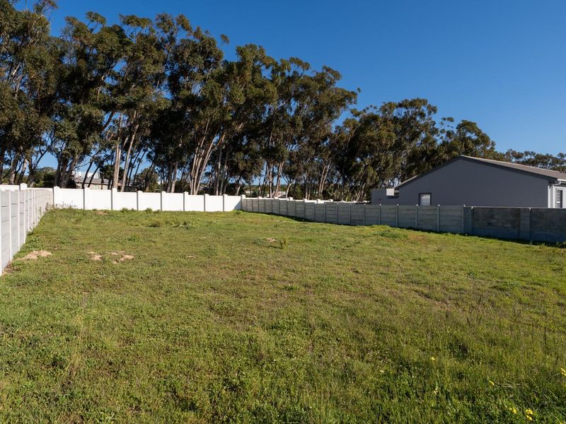 A vacant residential plot featuring a grass lawn and secure precast concrete boundary walls, ready for development.