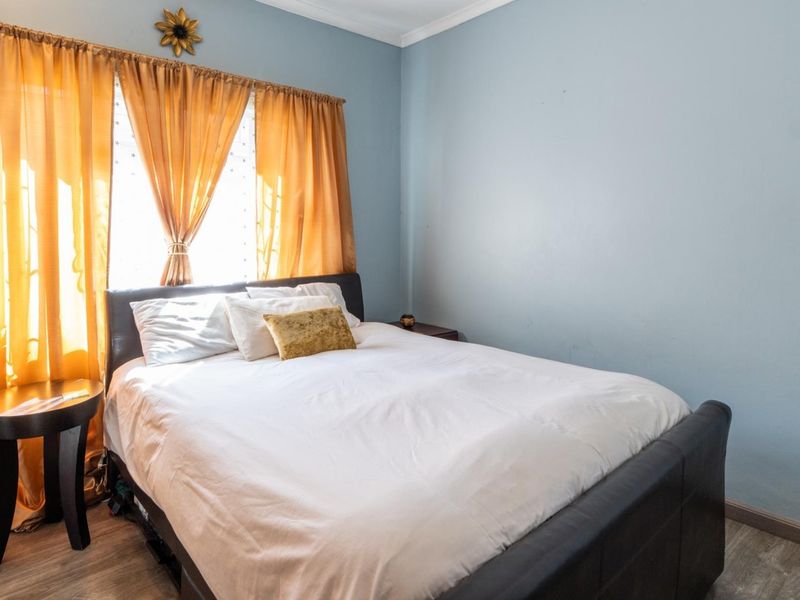 A bedroom featuring light blue walls, laminate flooring, and decorative cornice detailing.
