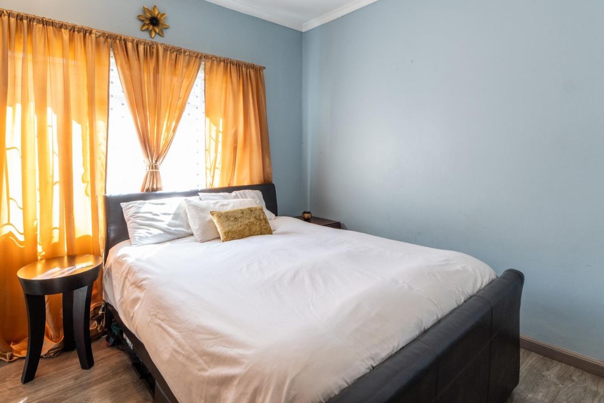 A bedroom featuring light blue walls, laminate flooring, and decorative cornice detailing.