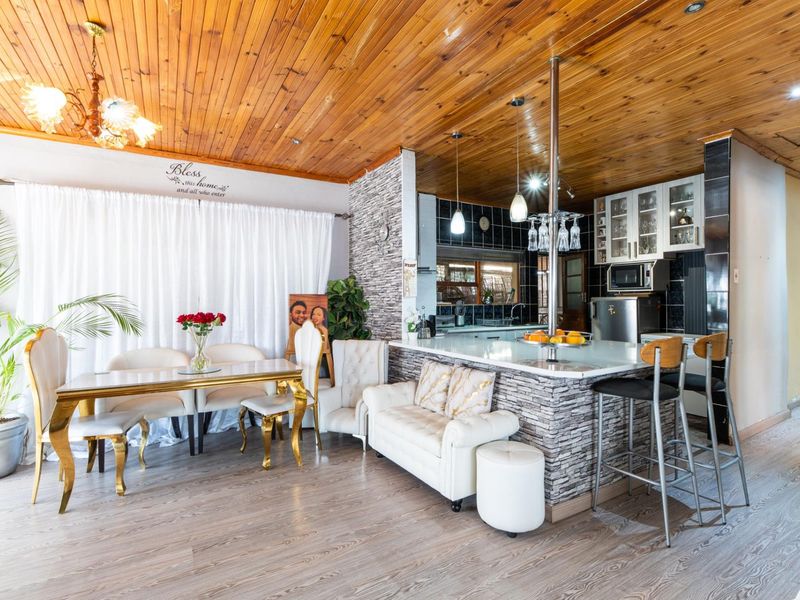 Open-plan living and kitchen area featuring a timber-clad ceiling, stone veneer breakfast bar, and modern laminate flooring.