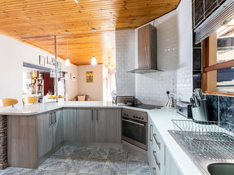 Modernized kitchen featuring light wood cabinetry, stone countertops, subway tile backsplash, and a distinctive timber tongue and groove ceiling.