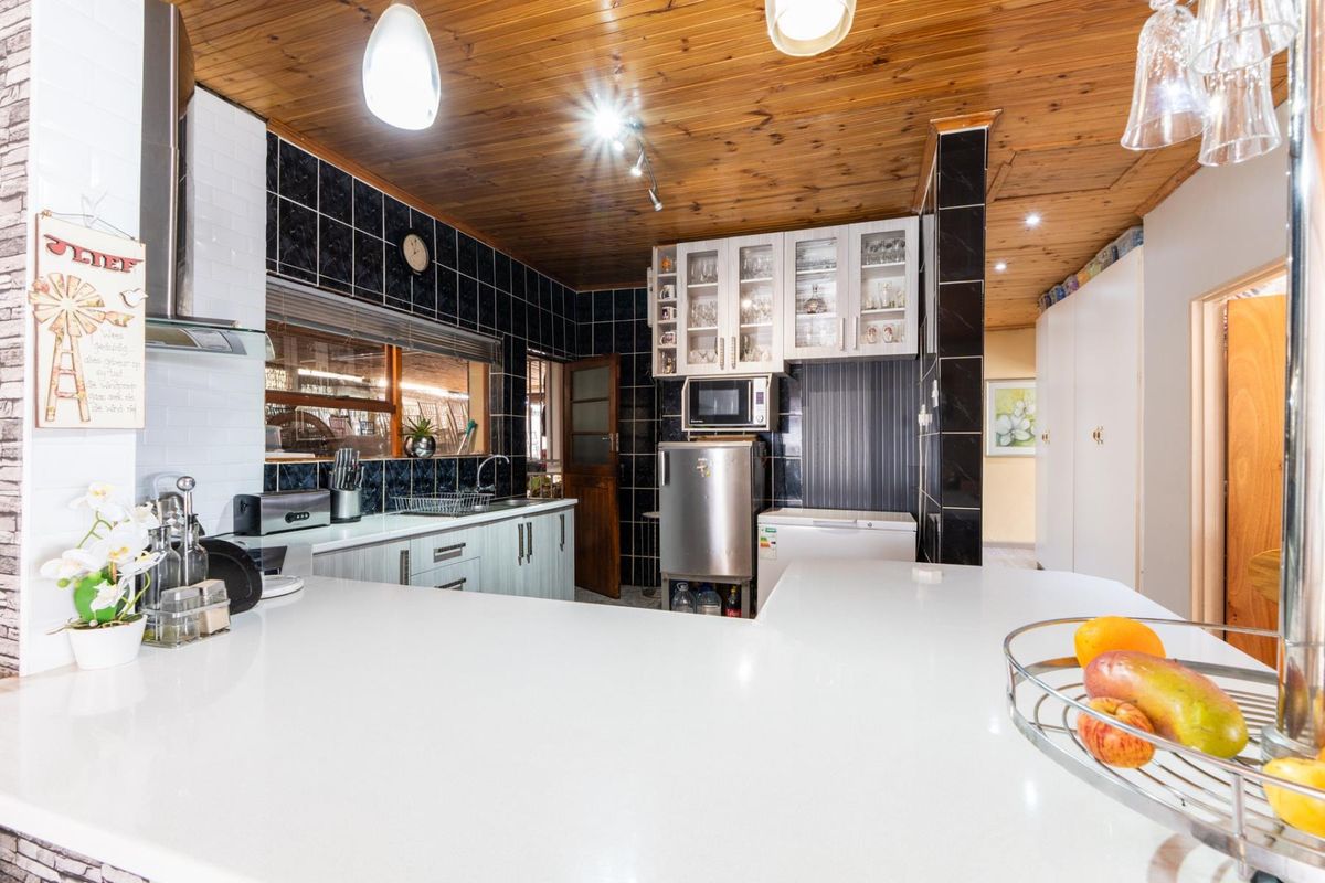 A functional kitchen featuring a breakfast bar, timber ceiling, built-in cabinetry, and a tiled backsplash, offering a practical layout for daily meal preparation.