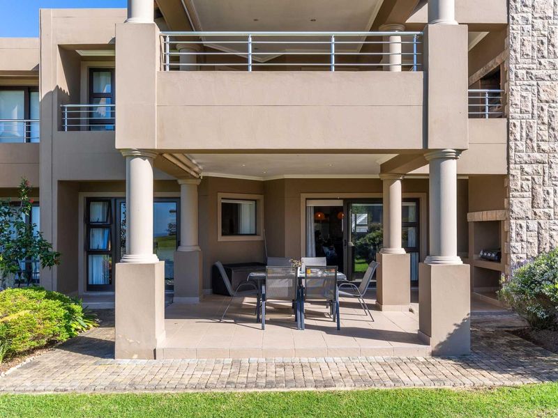 Spacious covered patio featuring tiled flooring, a built-in braai, and stone cladding, providing seamless access to the interior through sliding glass doors.
