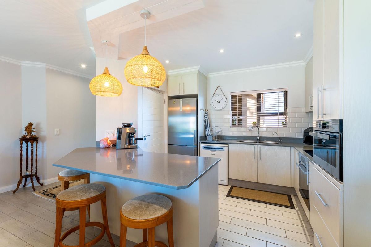 Modern kitchen featuring quartz countertops, subway tile backsplash, built-in oven, and a breakfast bar island with pendant lighting.