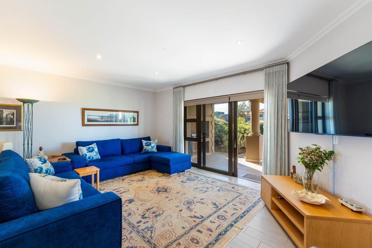 A bright and well-maintained living room featuring tiled floors, recessed lighting, and large sliding glass doors providing direct access to an outdoor patio area.