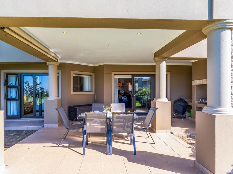 A spacious covered patio featuring tiled flooring, recessed lighting, and a built-in braai area, providing a seamless transition to the interior living space.