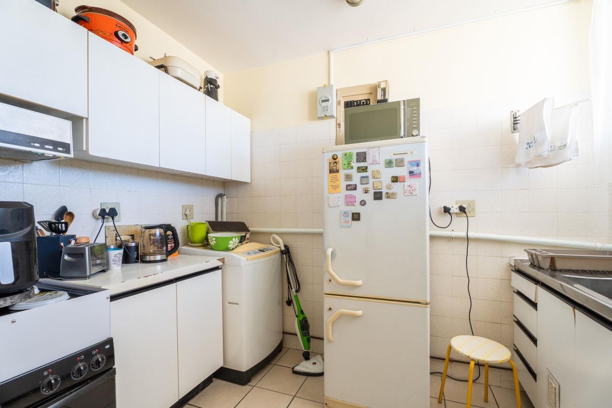 A functional kitchen space featuring built-in cabinetry, tiled backsplash, and tiled flooring, offering a practical layout for daily use.