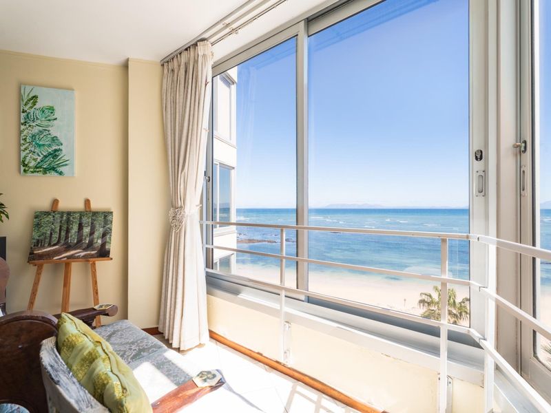 Enclosed balcony featuring large sliding glass doors with expansive, unobstructed ocean and beach views.