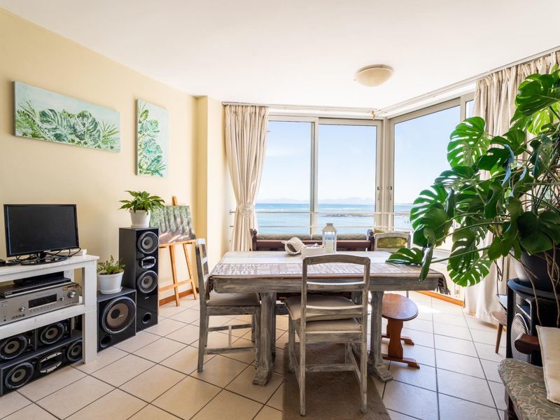 Bright living area featuring large sliding glass doors with ocean views and neutral tiled flooring.