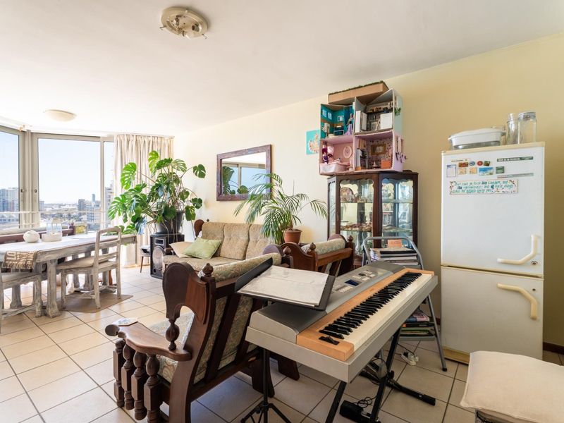 Open plan living and dining area featuring tiled flooring and large sliding glass doors with access to a balcony and city views.
