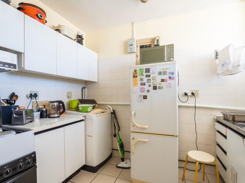 A functional kitchen space featuring built-in cabinetry, tiled backsplash, and tiled flooring, offering a practical layout for daily use.