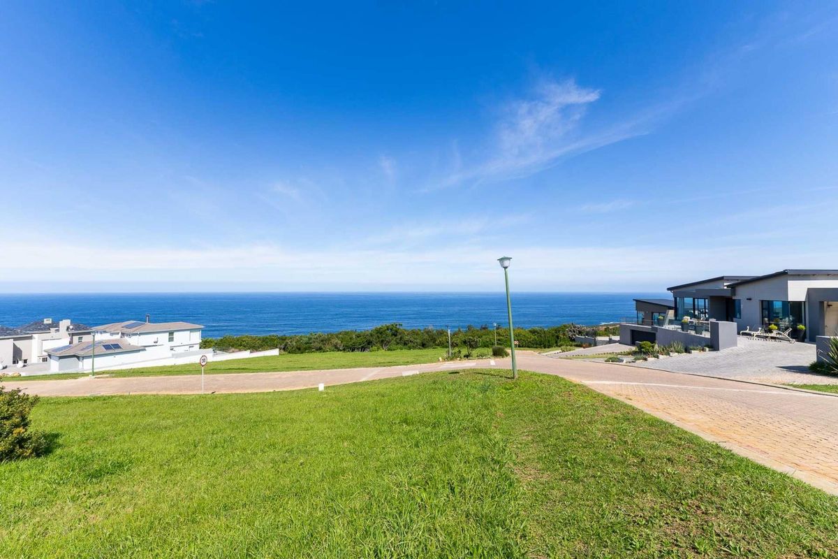 A scenic view of the ocean from a residential plot, featuring paved roads and surrounding coastal landscape.