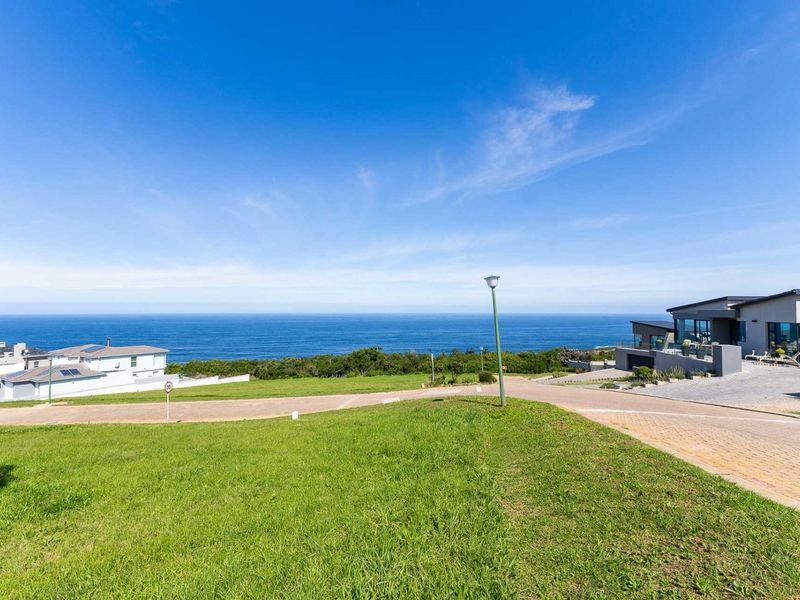 A scenic view of the ocean from a residential plot, featuring paved roads and surrounding coastal landscape.