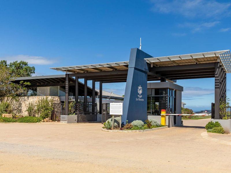 The secure entrance gatehouse of Le Grand estate, featuring modern architectural design, stone accents, and integrated solar panels.