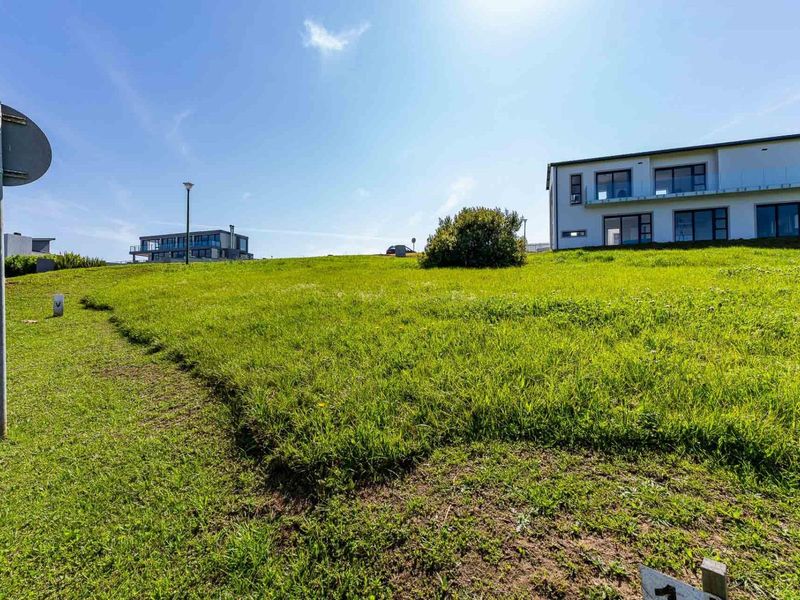 A view of a vacant residential plot featuring a grass lawn with a street light, situated in a developed neighborhood.