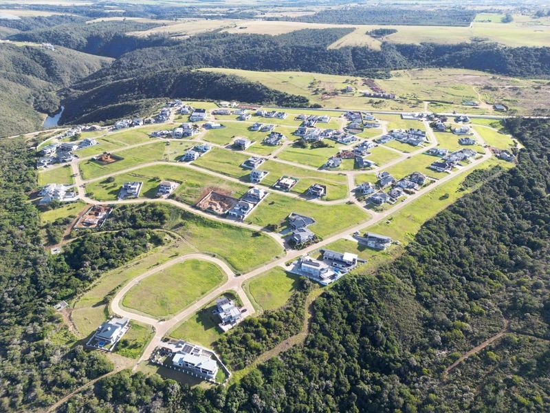 An aerial view of a residential estate development featuring multiple plots, paved road infrastructure, and surrounding natural landscape.