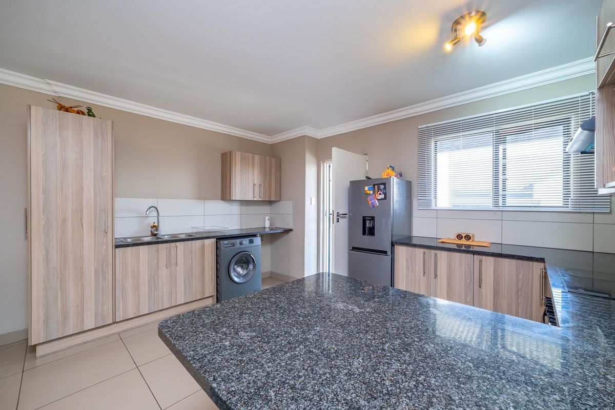 Modern kitchen featuring granite countertops, ample built-in cabinetry, tiled backsplash, and tiled flooring, offering a functional and well-maintained workspace.