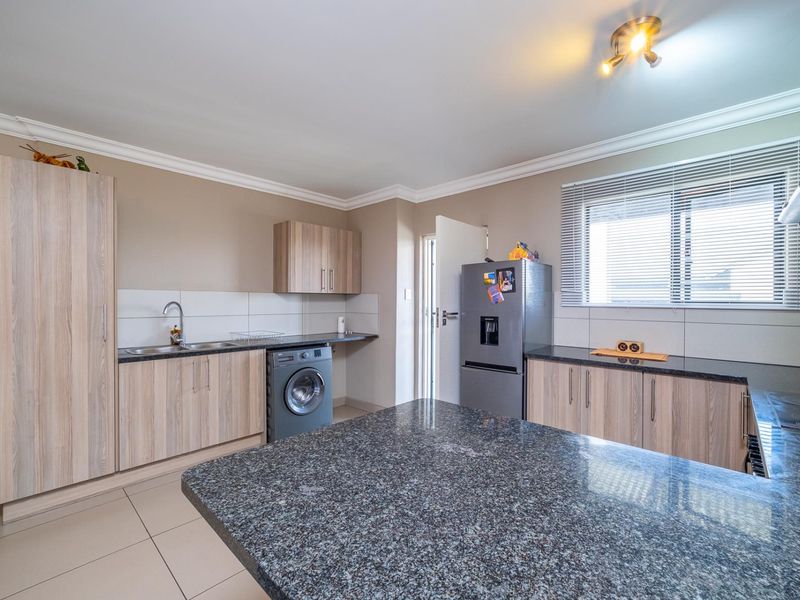 Modern kitchen featuring granite countertops, ample built-in cabinetry, tiled backsplash, and tiled flooring, offering a functional and well-maintained workspace.