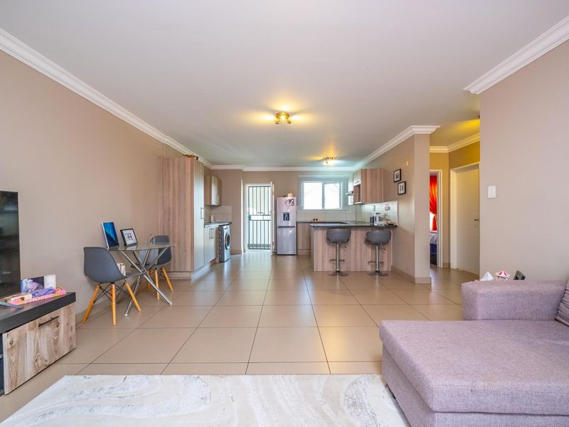 Spacious open-plan living area featuring tiled floors, a modern kitchen with a central island, and neutral wall tones throughout.