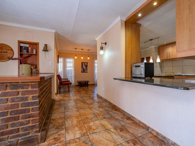 Open plan living area featuring a brick bar counter, tiled flooring, and a kitchen with granite countertops and built-in cabinetry.
