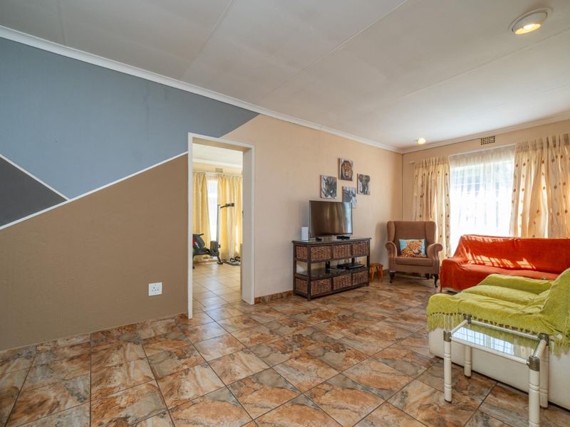 A living room featuring tiled flooring and a doorway leading to an adjacent room, providing a functional and connected living space.