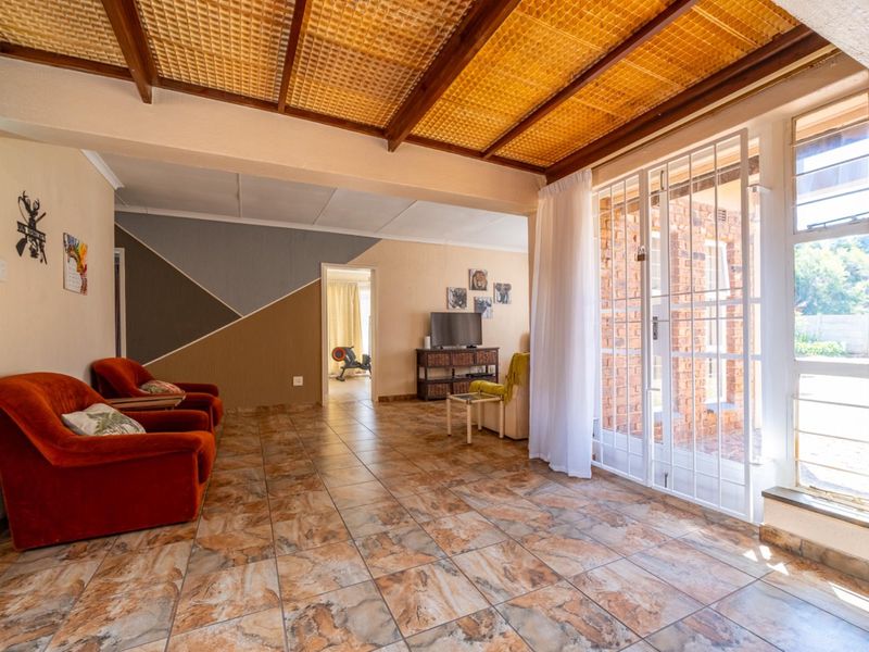 Spacious living area featuring tiled flooring, a unique exposed beam ceiling, and direct access to the exterior through a secure glass sliding door.