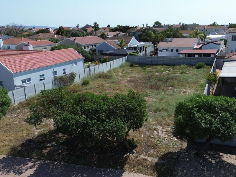 Aerial view of a vacant residential plot surrounded by established suburban housing and enclosed by precast concrete boundary walls.