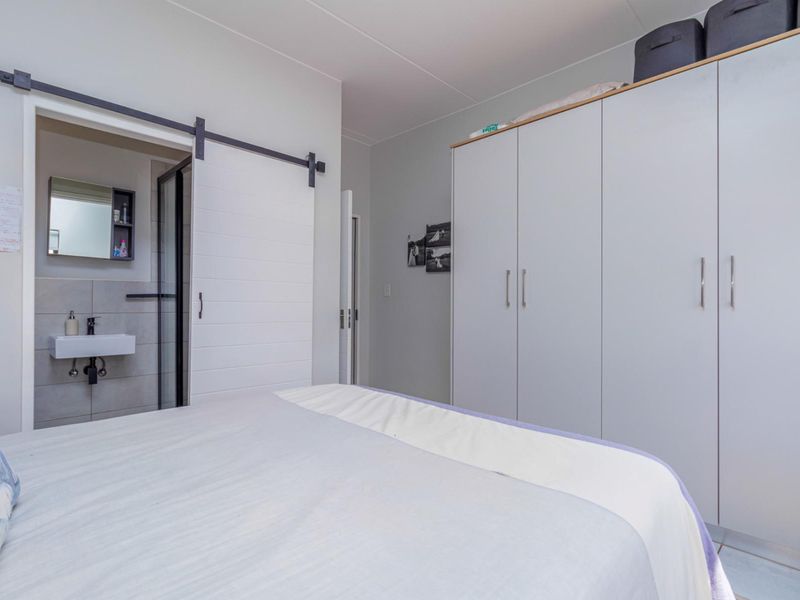 A well-maintained bedroom featuring a large built-in wardrobe, modern sliding barn door, and direct access to an en-suite bathroom.