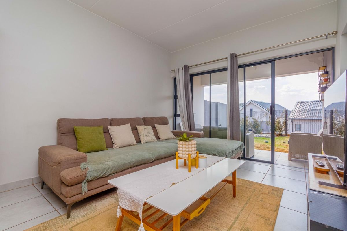 A bright living room featuring tiled flooring and large sliding glass doors that provide direct access to the outdoor patio area.