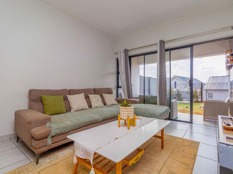 A bright living room featuring tiled flooring and large sliding glass doors that provide direct access to the outdoor patio area.