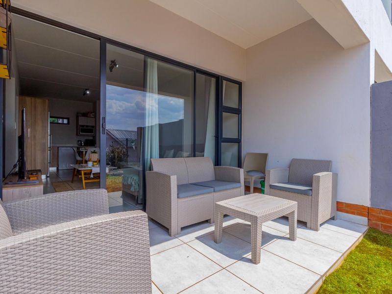 A covered patio area featuring tiled flooring and large sliding glass doors providing seamless access to the interior living space.