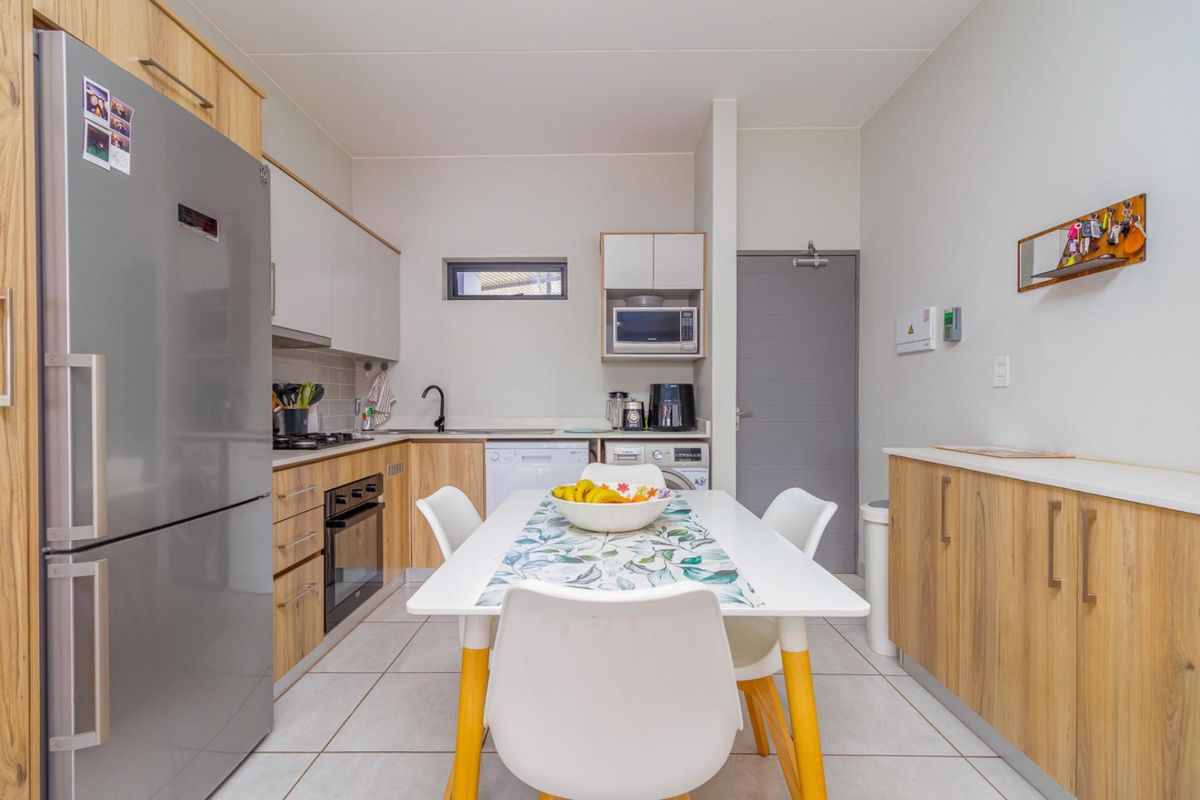 Modern kitchen featuring light wood-tone cabinetry, integrated appliances, gas hob, electric oven, and tiled flooring, offering a functional and contemporary cooking space.